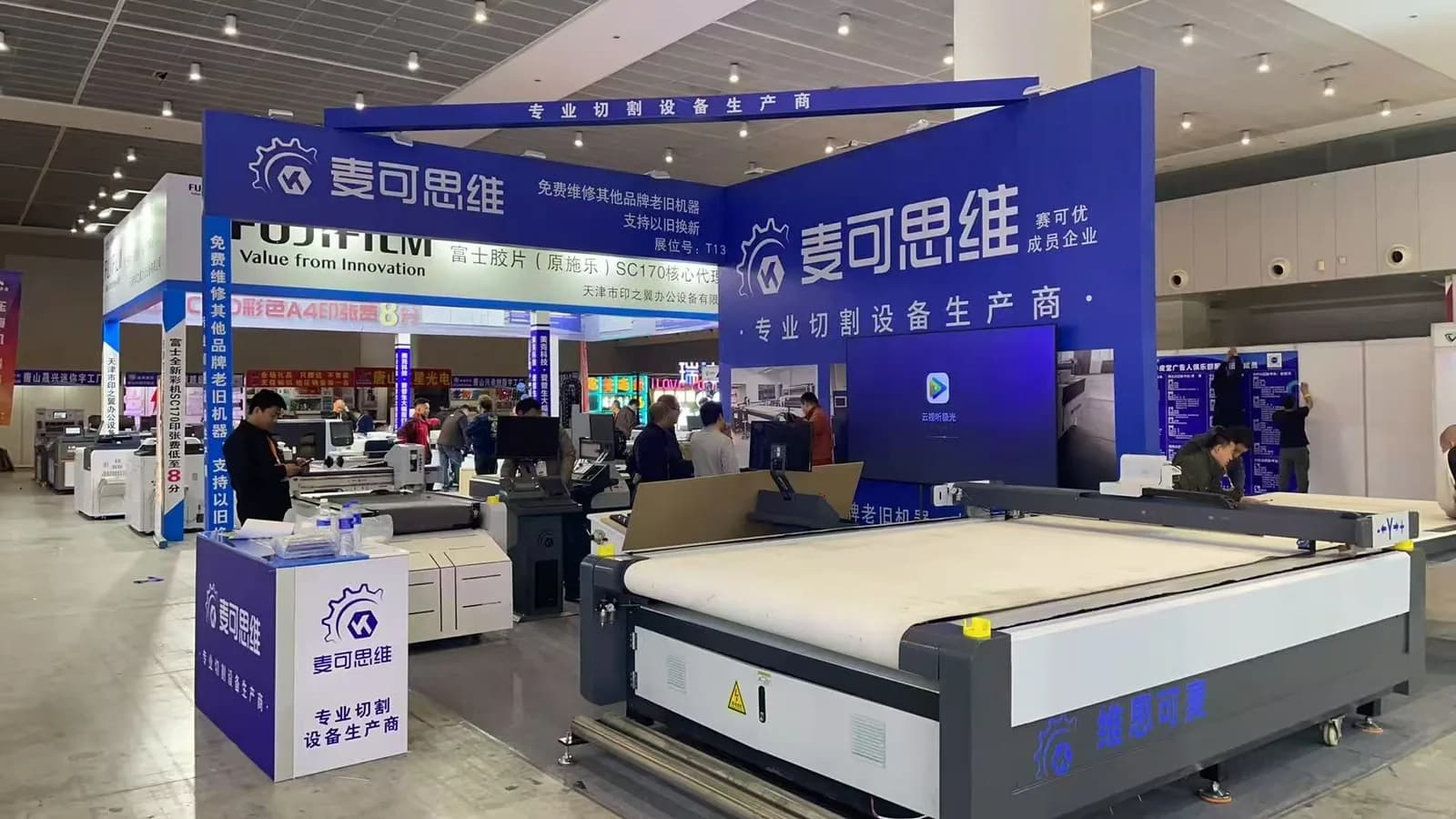 Completed blue exhibition booth with large-format graphics and cutting equipment on display