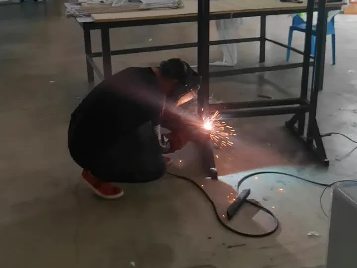Worker joining a rectangular metal display frame in a workshop